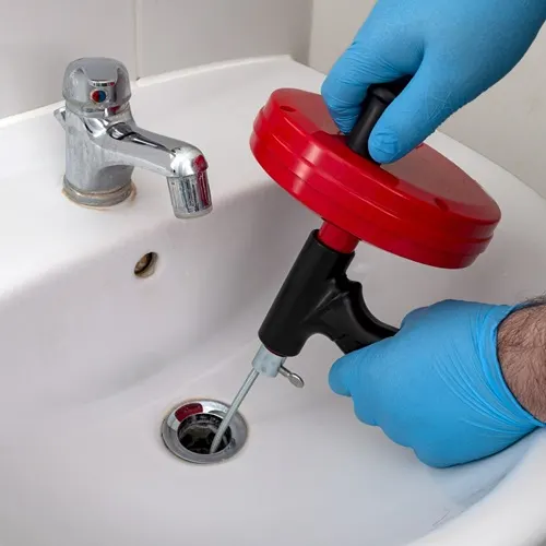 Plumber using drain snake tool